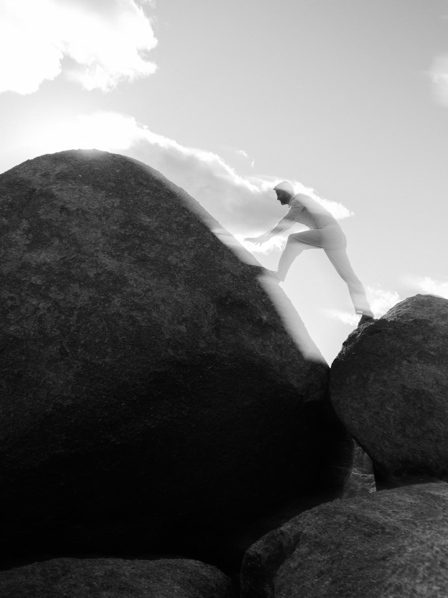 A person climbing the shoulder of a granite boulder