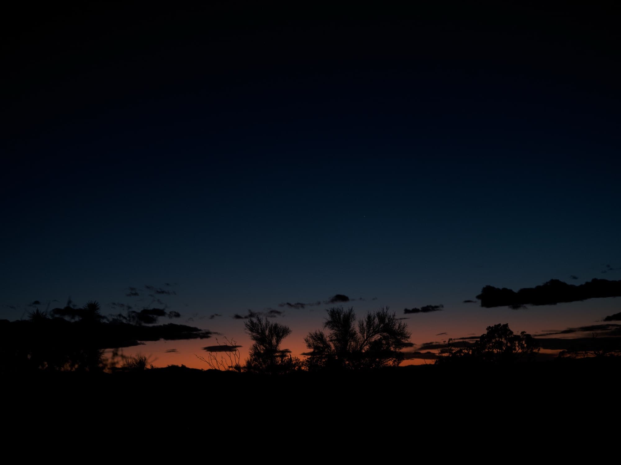 The last band of orange light along the desert horizon after sunset
