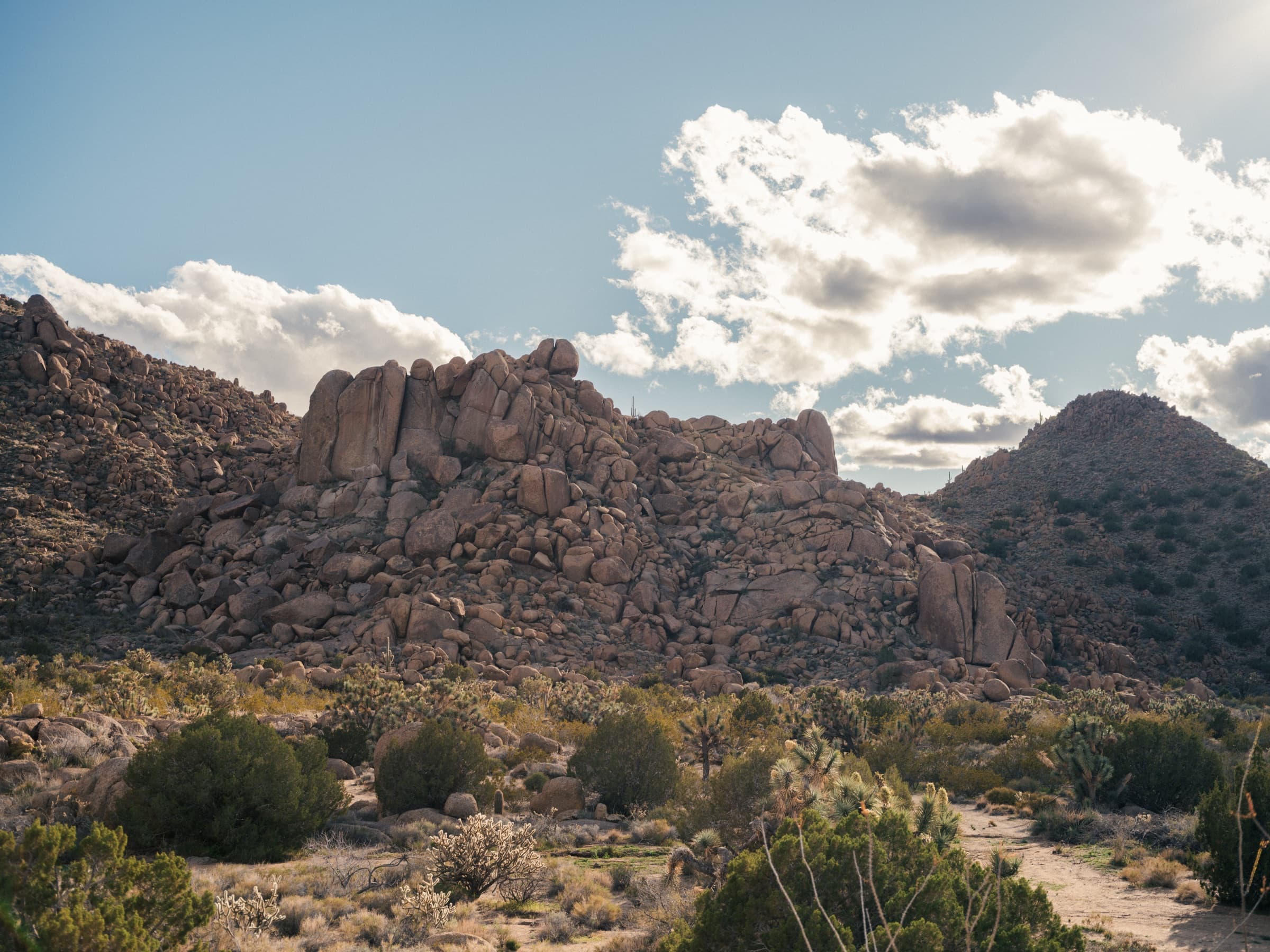 The wide boulder massif below the granite peaks under high cloud