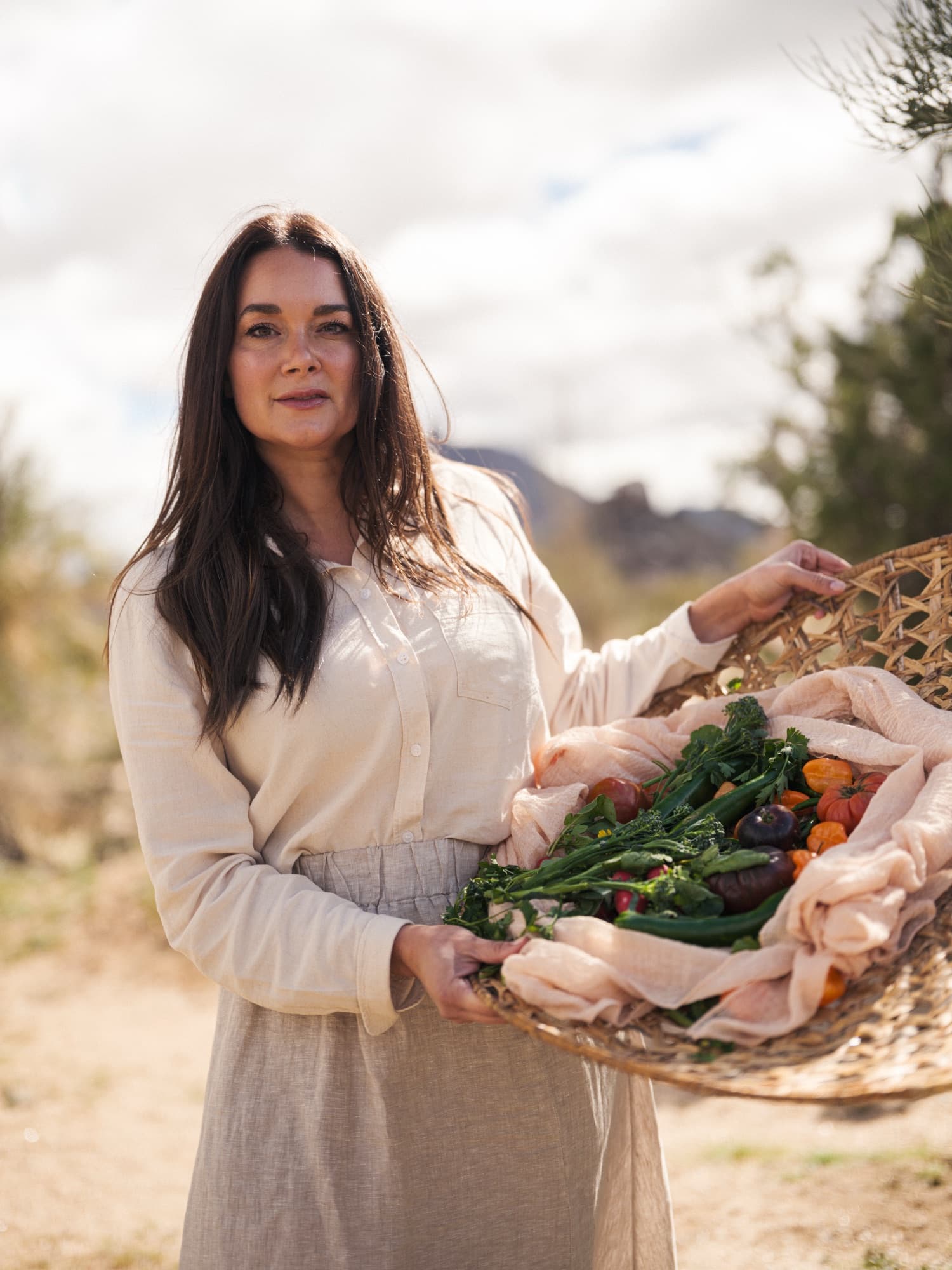 A woman carrying a woven basket of just-cut vegetables from the farm